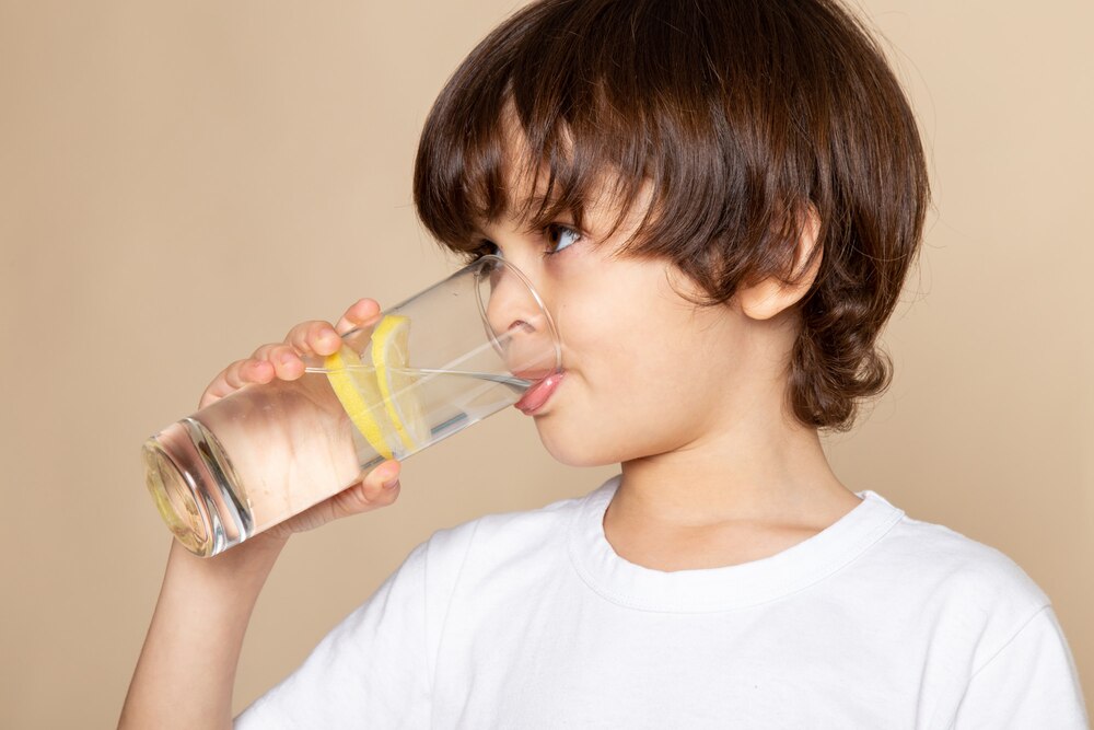 little boy cute drinking lemon juice on pink